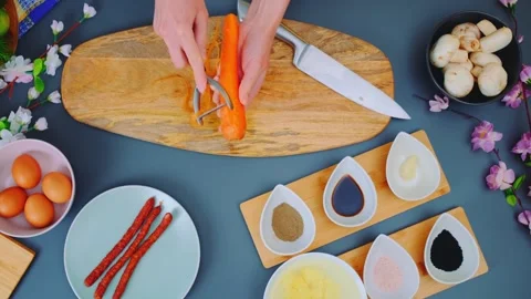 Hands peeling carrot with vegetable peeler on wooden cutting board indoors Stockbeeldmateriaal 342857345