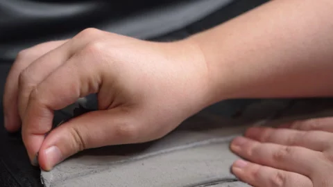 Hands peeling flaking black coating from gray fabric surface in close view Stock Footage 347181237