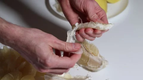 Hands peeling a juicy pomelo segment, preparing a healthy snack. Stock Footage 326977074