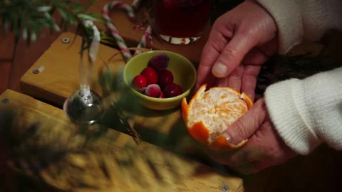 Hands peeling orange fruit through view of Christmas tree 库存影片 327222359