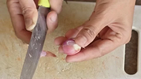 Hands peeling the outer skin of small red shallot with sharp kitchen knife .. Stock Footage 324822687