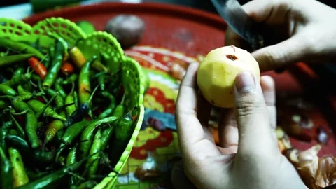 Hands Peeling a Potato with Vegetables, A close-up of hands peeling a potat.. Stockbeeldmateriaal 304978343