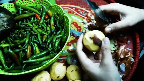 Hands Peeling a Potato with Vegetables, A close-up of hands peeling a potat.. 動画素材 304978362