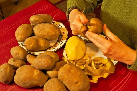 Hands peeling raw potatoes preparing healthy food Stock Photos