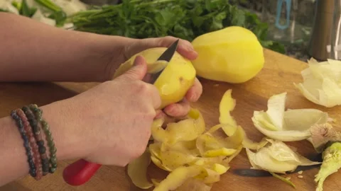 Hands peeling raw yellow potato with a knife on wooden cutting board Stock-Footage 331313984
