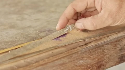 Hands peeling off a thin layer of wood from an old weathered plywood table .. Video stock 324823972