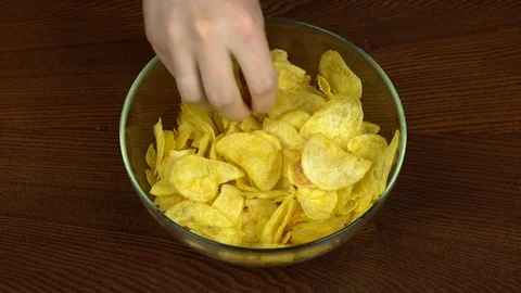 The hands of people actively taking chips from a large dish. The company of 스톡 동영상 117536363