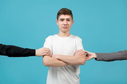 Hands of people behind the scenes pulling somewhere a young guy in a white T- Stock Photos