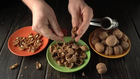 Hands of a person cracking open walnuts and separating the shells from the nuts Stock Footage 328510604
