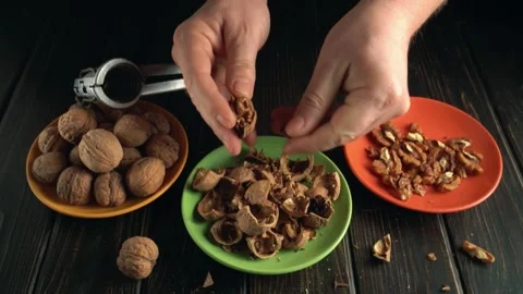Hands of a person cracking open walnuts with a nutcracker, sorting shells and Video stock 336024647