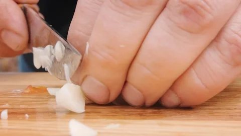 Hands of person cutting fresh garlic into small pieces Stock Footage 247761853