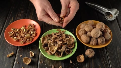 Hands of a person shelling walnuts, separating shells from nuts in colorful Stock Footage 328237646