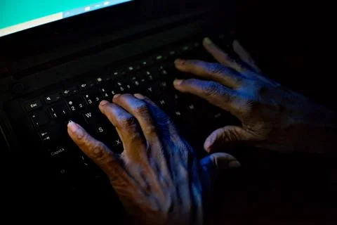 Hands of a person using a computer keyboard to spread fake news Stock Photos