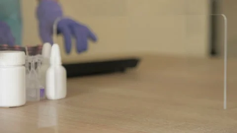 Hands of a pharmacist in protective gloves serve medicines to a client. Virus Stock Footage 127439117