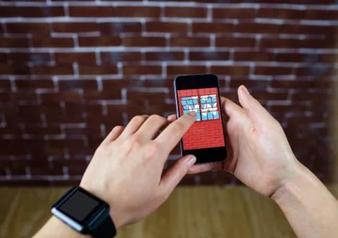 Hands with phone in front of a brick wall. In the phone the design of the new Foto stock