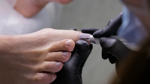 Hands of the physician of the podologist make a hardware pedicure Stock Footage 123217677