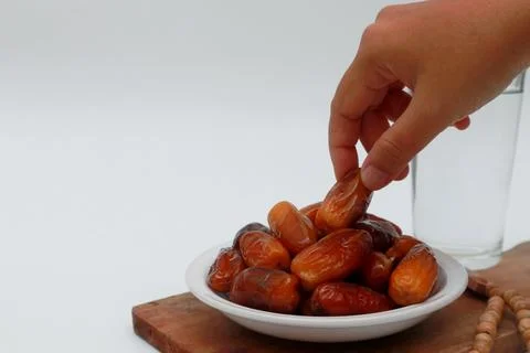 Hands pick up dates on a white plate. Preparing to break the fast Stock Photos
