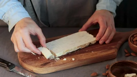 A hands pick up a freshly broken piece of hard Spanish Turron de Alicante, a  Stock Footage 331378974