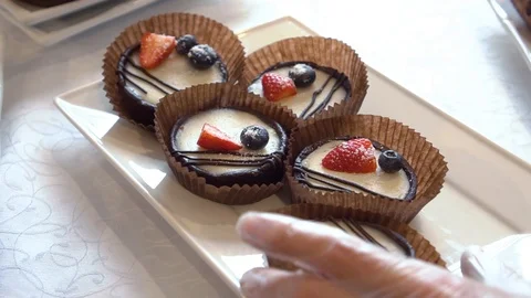 Hands pick up tartlets dessert from white plate Video stock 119664332