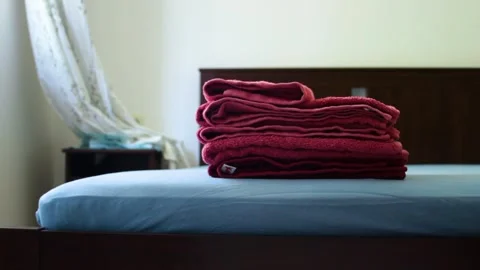 Hands pick up towels stacked on bed in hotel room Stock Footage 315560140