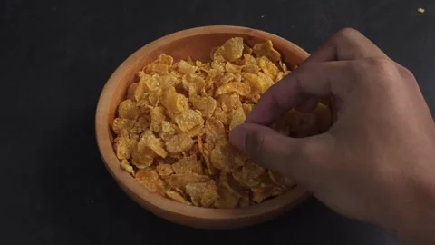 Hands picking corn flakes from wooden bowl Stock Footage 279700745