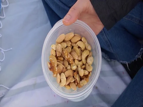 Hands Picking Mixed Roasted Nuts from a Plastic Container Stock Footage 331261697