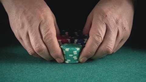 Hands picking up poker chips on a green felt table, showing a big win in a Stock Footage 338306654