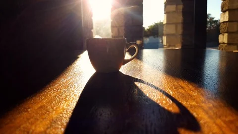 Hands picking steaming hot white coffee cup from wooden table. Light rays 스톡 동영상 105175568