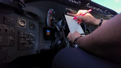 Hands of a Pilot Inside a Modern Jet Ccokpit Taking Notes in a Real Flight on a Stock Footage 333687265