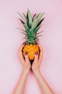 Hands with pineapple on stylish pink Stock Photos