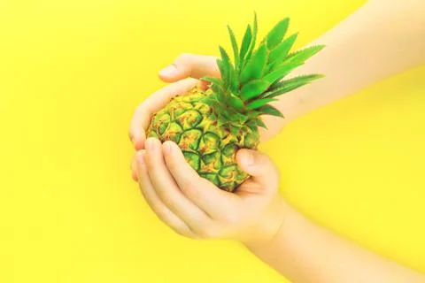 Hands with pineapple on summer neon yellow background Stock Photos
