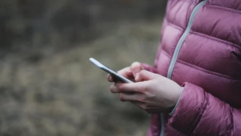 Hands in pink jaket holding while mobile phone Stock Footage