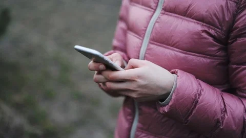 Hands in pink jaket holding while mobile phone Stock Footage 127316258