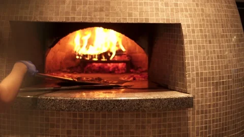 Hands of a pizza maker who puts pizza in the oven using a shovel. Fire burns Stock Footage 140920835