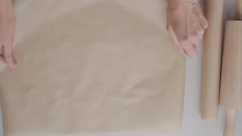 Hands place baking paper on table next to rolling pin during dough preparation Stock Footage 339470458