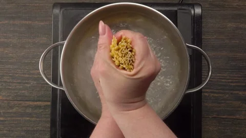Hands Place Spaghetti Bundle in Boiling Water Stock Footage 306461308