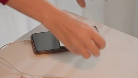 Hands place sticky note labeled listen on smartphone connected to charging cable Stock Footage 344404681