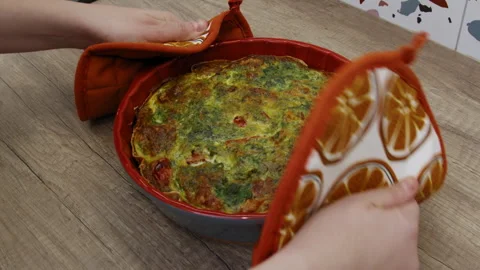 Hands placing a baking pan with quiche pie on a cork stand. Stock Footage 266425831