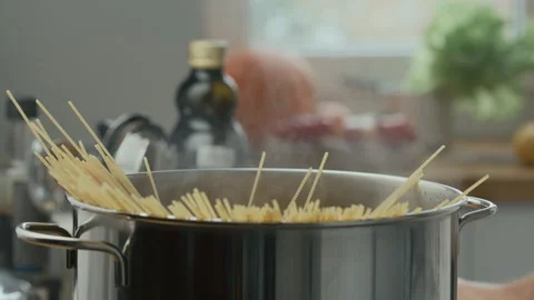 Hands Placing Bunch of Spaghetti into Pot of Boiling Water Stock Footage 288740101