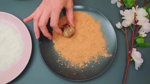 Hands placing chocolate truffle on powder in kitchen setting 库存影片 342871763