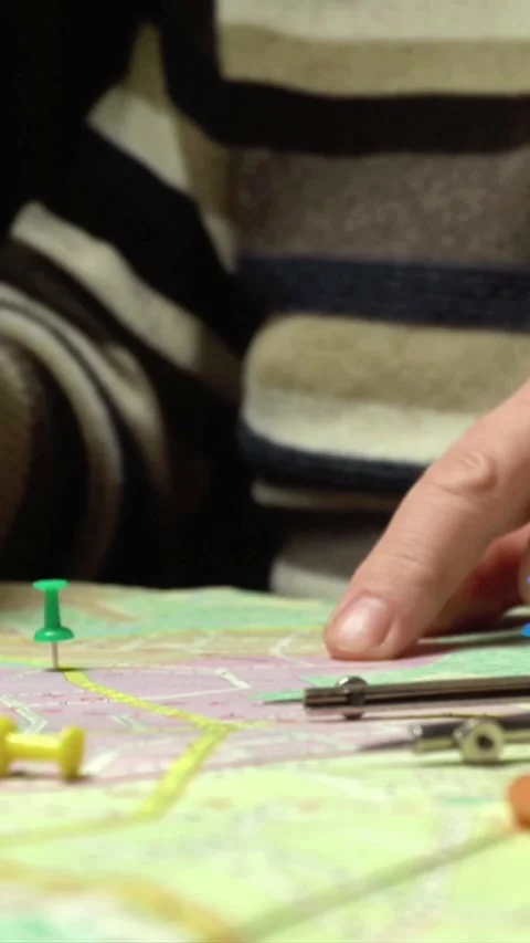 Hands placing colorful push pins on a detailed map while using a compass and Stock Footage 339810663