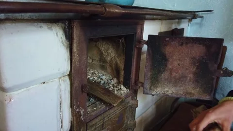 Hands placing firewood inside a rustic indoor wood-burning stove Stock-Footage 342028299