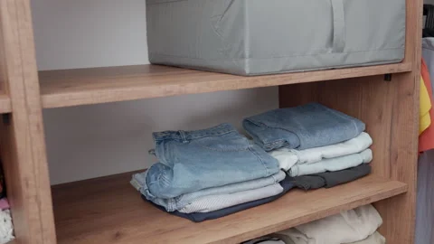 Hands placing folded clothes on wardrobe shelf Stock Footage 337832695