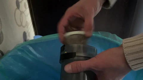 Hands placing kitchen waste into trash bin with blue bag, household recycling Stock Footage 335695011