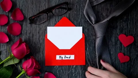 Hands placing a necktie next to a Fathers Day card with red roses Stock Footage 334105142