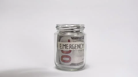Hands placing one hundred-dollar bills into a glass jar Stock Footage 317107861