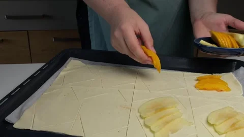 Hands placing peach slices on puff dough for baking, baking process filled .. Stock Footage 320956196