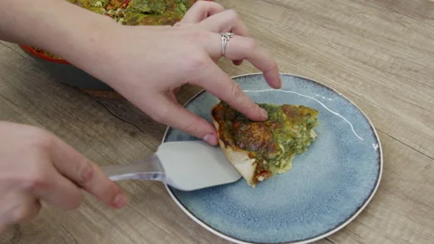 Hands placing a piece of quiche pie on a bluish plate. Stock Footage 266426382