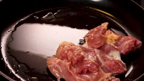 Hands placing raw poultry meat on hot frying pan. Video stock 171674367
