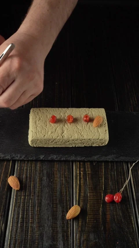 Hands placing red berries and almonds on a rectangular block of food using Stock Footage 332649394
